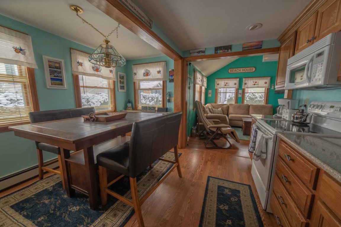 A wide view of an open-plan living area with a dining table, kitchenette, and living room.