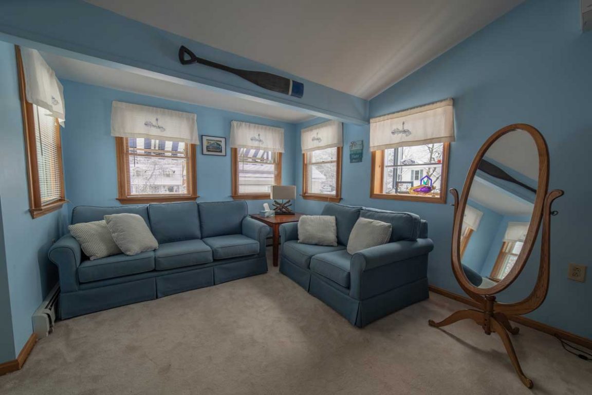 A living room with blue walls, two blue couches, a wooden coffee table, and a large mirror.