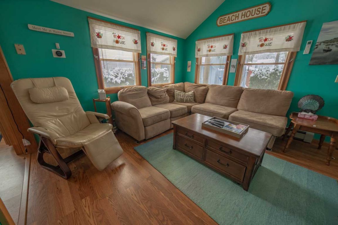 A living room with teal walls, a wooden floor, and a sectional sofa.