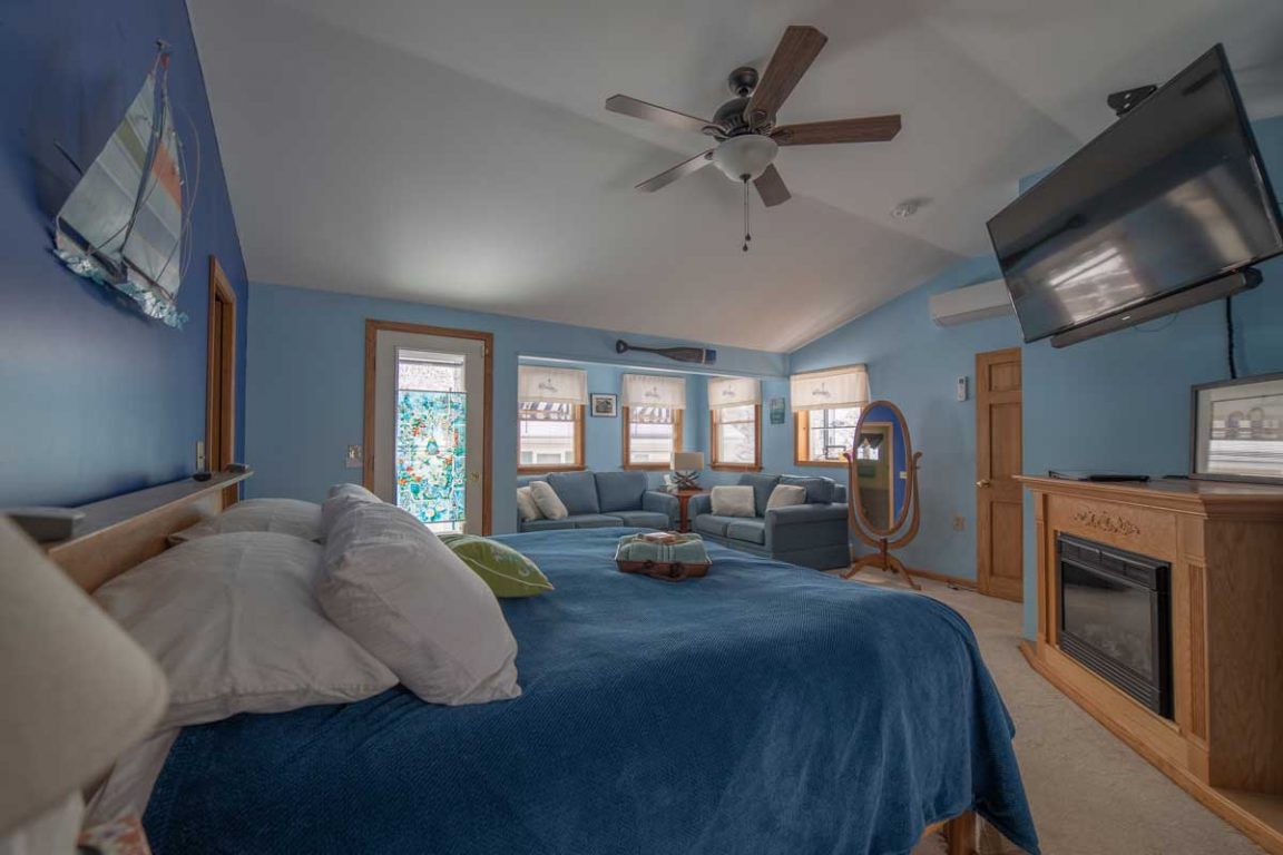 A wide view of a suite with a large bed, sofa, fireplace, and TV